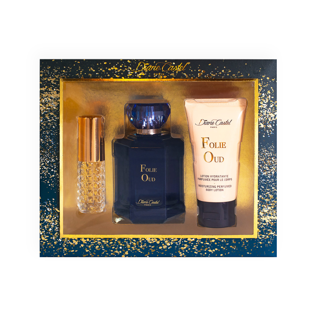 Coffret Parfum Folie Oud - Diane Castel. Ensemble luxueux comprenant une eau de parfum bleue élégante, une lotion hydratante parfumée pour le corps et un vaporisateur de sac doré. Présenté dans un coffret bleu nuit orné d'éclats dorés scintillants. Parfait pour une fragrance boisée, intense et sophistiquée.