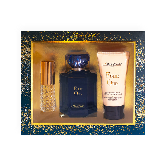 Coffret Parfum Folie Oud - Diane Castel. Ensemble luxueux comprenant une eau de parfum bleue élégante, une lotion hydratante parfumée pour le corps et un vaporisateur de sac doré. Présenté dans un coffret bleu nuit orné d'éclats dorés scintillants. Parfait pour une fragrance boisée, intense et sophistiquée.