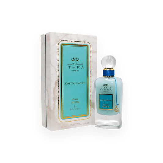 n flacon de parfum bleu pastel appelé "Cotton Candy Musk" de la marque Ithra Dubai par Ard Al Zaafaran. Le flacon élégant est surmonté d’un bouchon sphérique transparent et orné d’un cordon bleu avec un petit pendentif doré. L'emballage présente un design raffiné avec un fond marbré blanc et des accents dorés, encadrant une étiquette bleu clair assortie au flacon, portant le nom du parfum en arabe et en anglais.